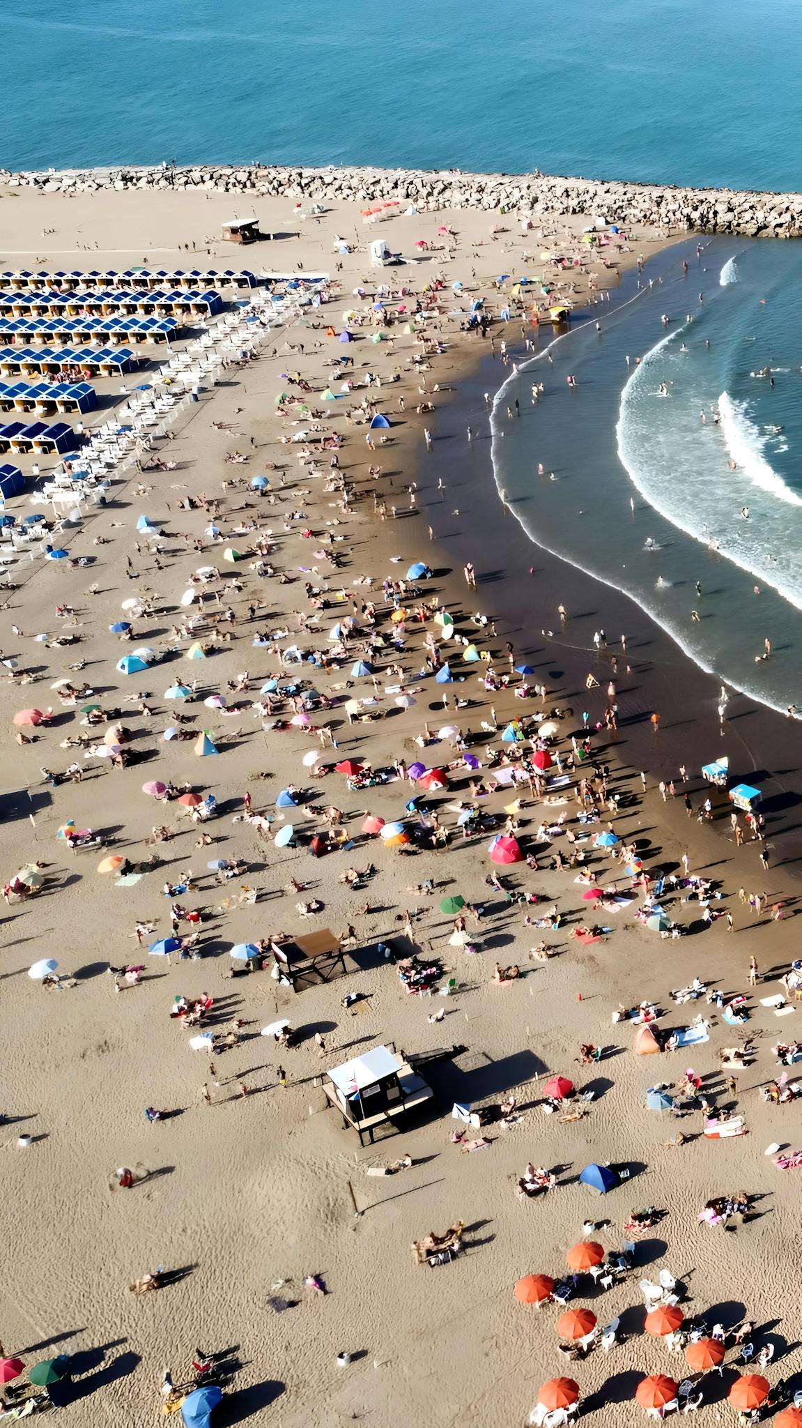 Vibrant aerial shot of Mar del Plata beach, Argentina, teeming with people enjoying summer sun and sea.
